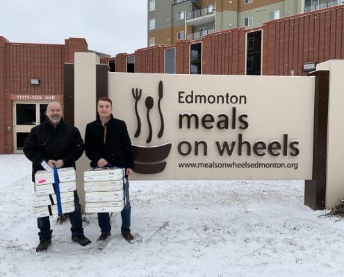 Novamen staff standing in front of Edmonton meals on wheels sign